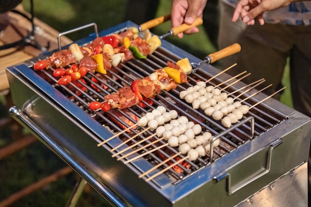 Barbecue spiedini di carne con verdure e polpette grigliate sulla griglia del barbecue a carbone nel cortile