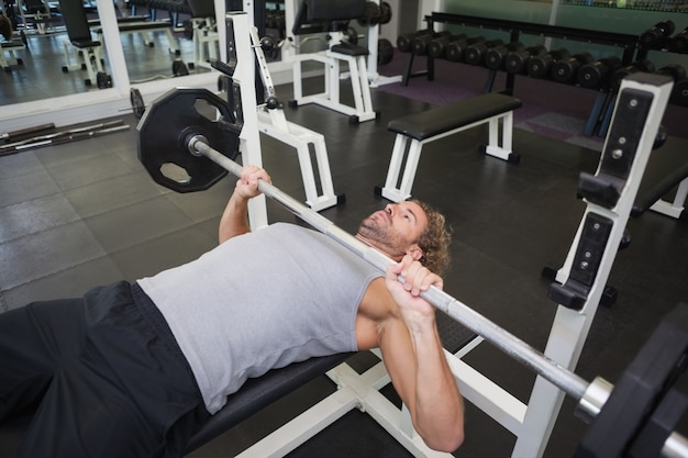 Barbell di sollevamento del giovane uomo muscolare in palestra