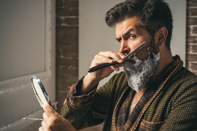 Barber Shop Studios.Sandalwood crema da barba. La preparazione dei capelli è solo per il ragazzo focoso. Cera per baffi. Parrucchiere e barbiere vintage. Barbiere vintage. Sta facendo lo styling con il rasoio.