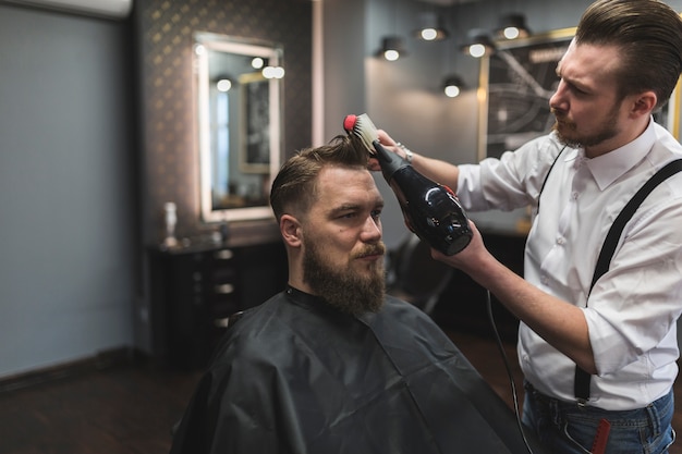 Barbiere che asciuga i capelli del cliente