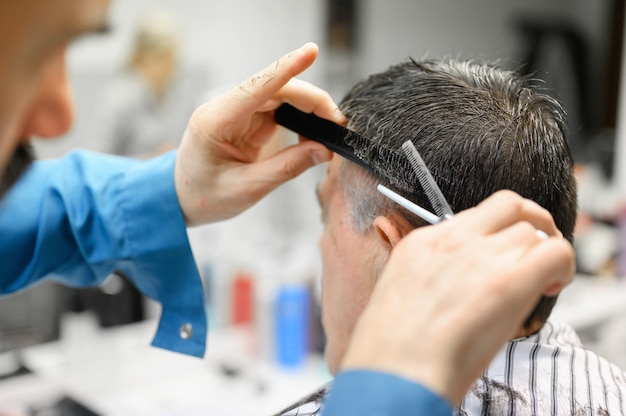 Barbiere che rifila i capelli dell'uomo anziano al negozio di barbiere.