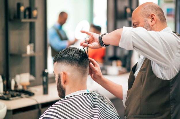 Barbiere che taglia i capelli nel negozio di barbiere