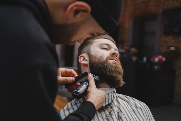 Barbiere che taglia la barba ad un cliente