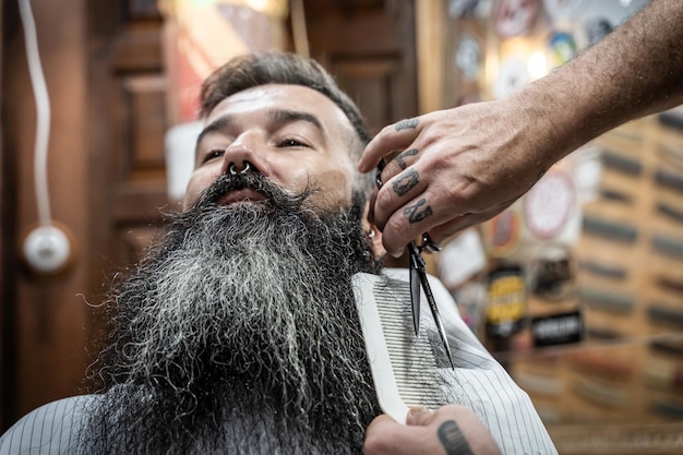 Barbiere che taglia la barba di un cliente