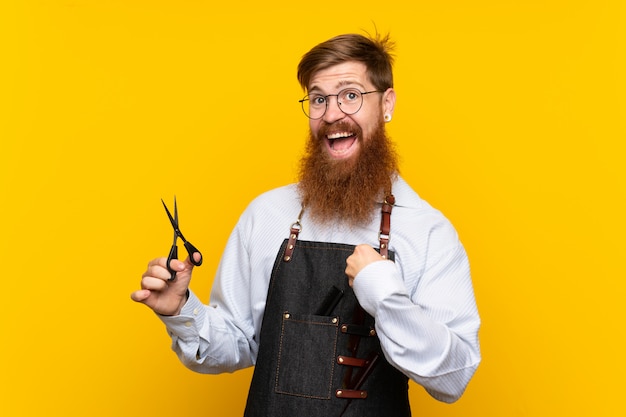 Barbiere con la barba lunga in un grembiule giallo con espressione facciale sorpresa