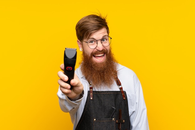 Barbiere con la barba lunga in un grembiule su sfondo giallo isolato