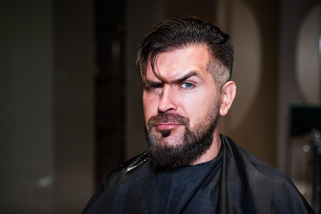 Barbiere maschio cura uomo barbuto in parrucchiere bellezza e moda capelli e barba styling ragazzo brutale visita barbiere professionista maestro hipster con capelli bagnati cura del viso