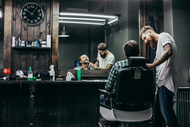 barbiere sorridente e attento mentre pettina la barba del suo cliente