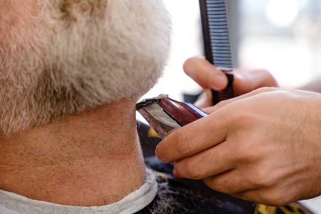 Barbiere taglio e taglio uomo barbuto con macchina da barba nel negozio di barbiere Processo di acconciatura