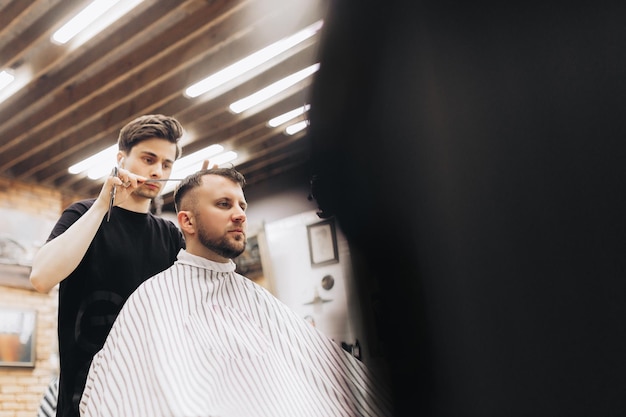 Barbiere tosatura della barba all'uomo nel negozio di barbiere che incornicia l'attaccatura dei capelli rasoio elettrico vintage tinto di marrone