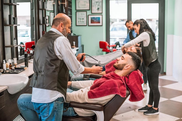 Barbieri professionisti che lavorano con i clienti nel negozio di barbiere