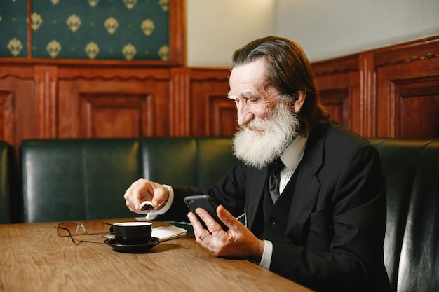 Barbuto anziano uomo d'affari. L'uomo con il caffè. Senior in abito nero.