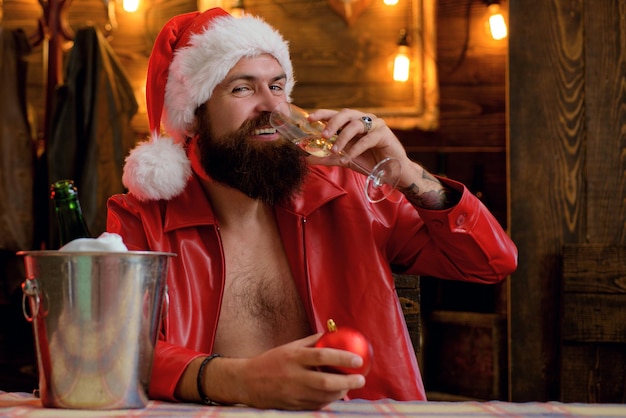 Barbuto bell'uomo babbo natale con la barba sorride e beve champagne luci di natale ghirlanda allegra...