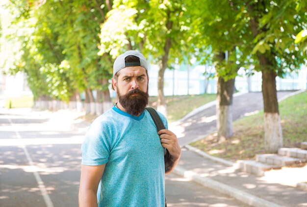 Barbuto e brutale. Uomo barbuto su fondo urbano. Hipster barbuto serio in stile casual in estate all'aperto. Ragazzo caucasico che indossa baffi e barba sul viso barbuto.