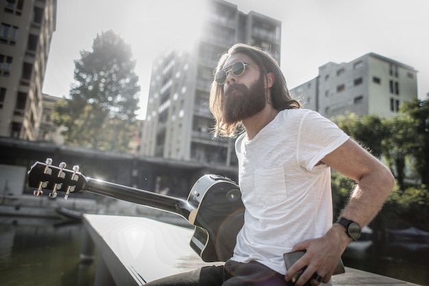 Barbuto uomo alla moda con una chitarra