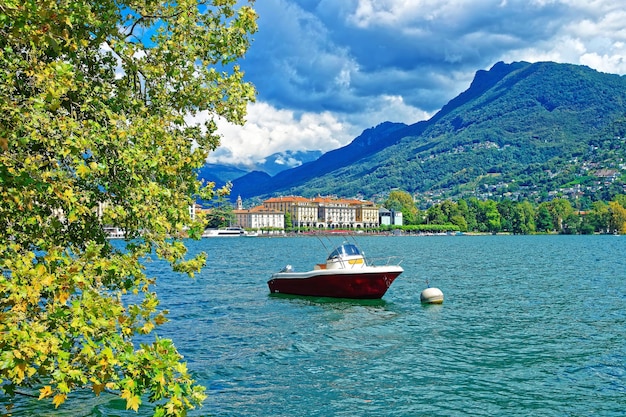 Barca a motore sul lungomare del lussuoso resort di Lugano sul Lago di Lugano e sulle montagne delle Alpi del Canton Ticino, Svizzera.