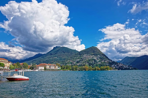 Barca a motore sul lungomare del lussuoso resort di Lugano sul Lago di Lugano e sulle montagne delle Alpi nel canton Ticino in Svizzera.