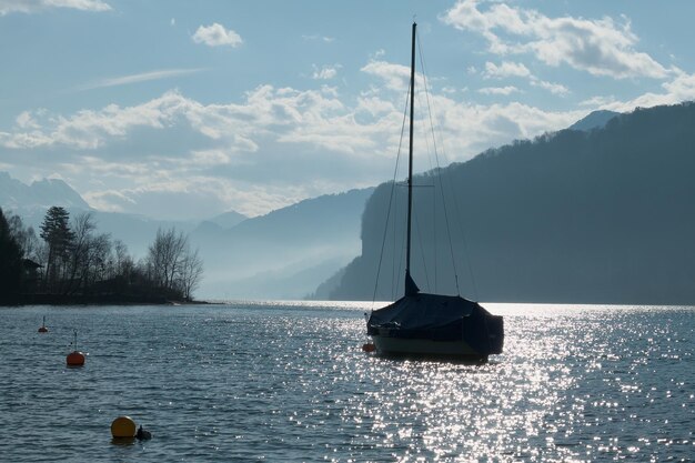 Barca a vela che naviga nel lago contro il cielo