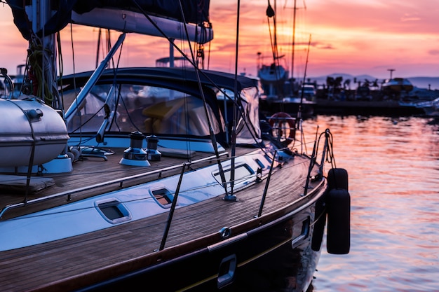 Barca a vela con la piattaforma di legno che sta nel marinaio al bello tramonto