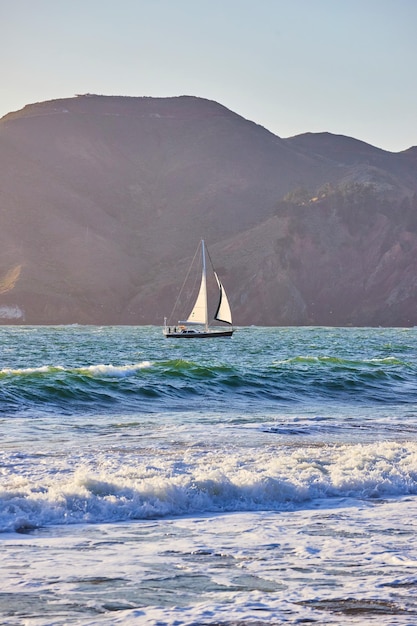 Barca a vela da montagne e onde vicino alla spiaggia