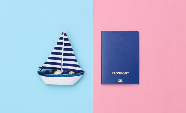 Barca a vela e passaporto su sfondo rosa blu. Concetto di viaggio minimalista. Vista dall'alto. Lay piatto