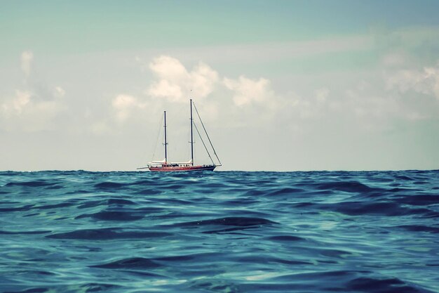 Barca a vela in legno che naviga all'orizzonte, mare blu aperto