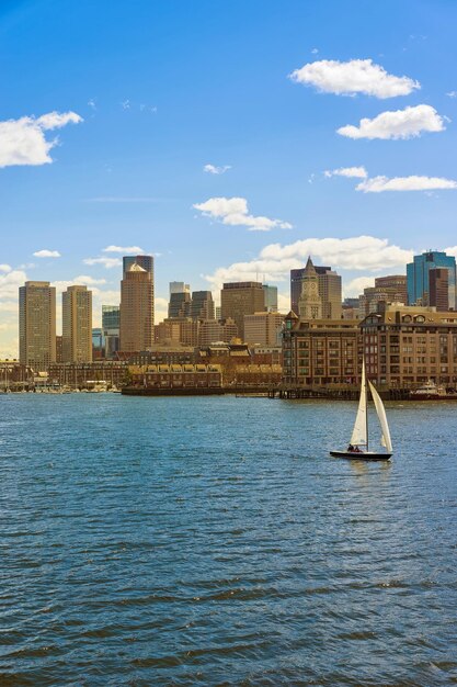 Barca a vela solitaria che galleggia davanti allo skyline di Boston negli Stati Uniti.