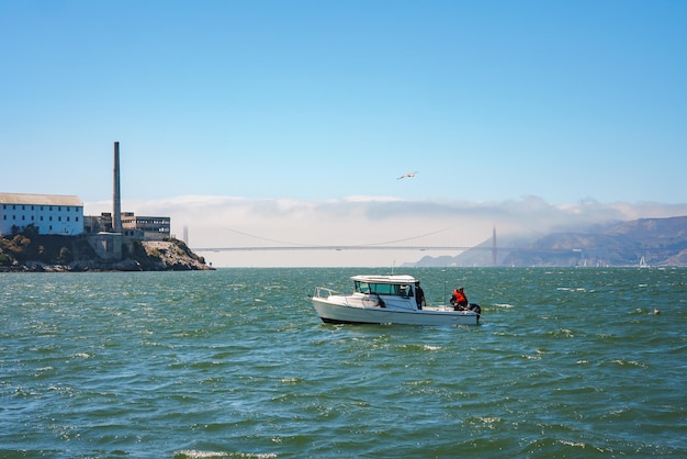 Barca che naviga nella baia di San Francisco con Alcatraz e il Golden Gate Bridge sullo sfondo