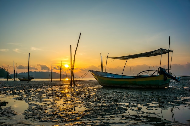 Barca da pesca sulla spiaggia quando sorge il sole