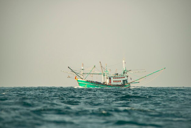 Barca da pesca tailandese tradizionale dipinta in bianco verde che naviga attraverso le acque del mare delle Andamane