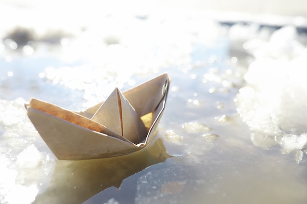 Barca di carta nell'acqua per strada. Il concetto di inizio primavera. Neve che si scioglie e una barca origami sulle onde dell'acqua.