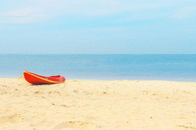 Barca rossa sulla spiaggia con bellissimo mare blu e cielo