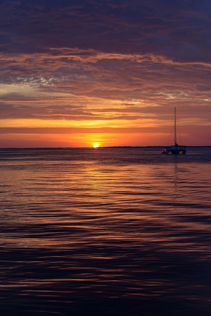 Barca sull'oceano al tramonto barche a vela con vele yacht da mare che navigano lungo l'acqua