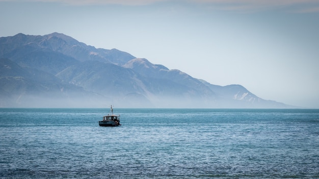 Barca sull'oceano con sfondo di montagna girato nella penisola di Kaikoura in Nuova Zelanda