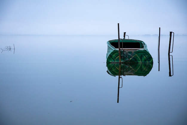 barca vuota parcheggiata sul lago prima dell'alba. paesaggio mattutino per la pesca. nessuno