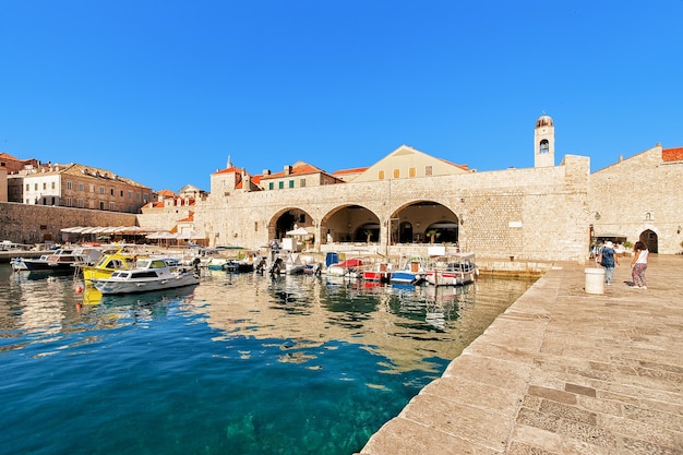 Barche al porto vecchio nel mare Adriatico a Dubrovnik, Croazia. Campanile del monastero domenicano e persone sullo sfondo