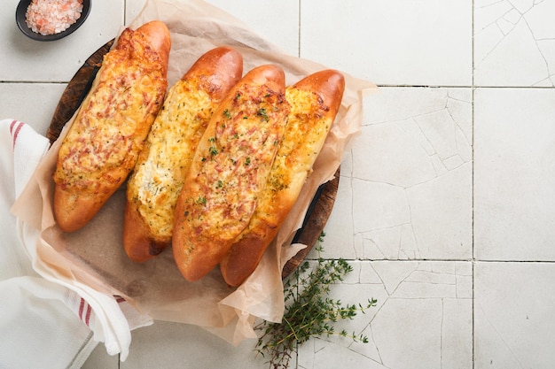 Barche Baguette Panino caldo al forno su pane baguette con prosciutto, pancetta, verdure e formaggio su pergamena e supporto in legno su sfondo grigio cemento Vista dall'alto Spazio di copia