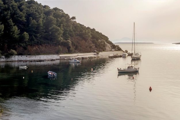 Barche da pesca e uno yacht sul molo sullo sfondo del mare e delle montagne