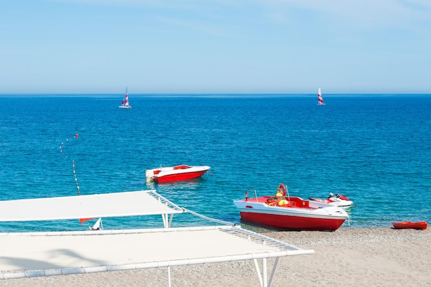 Barche rosse sulla spiaggia e yacht in mare. Bellissimo mare a Kemer, in Turchia.