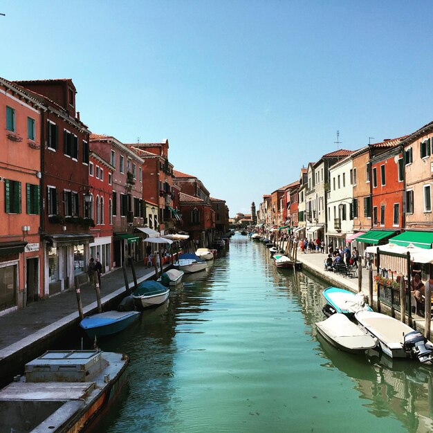 Barche sul canale in mezzo agli edifici contro il cielo blu limpido in città