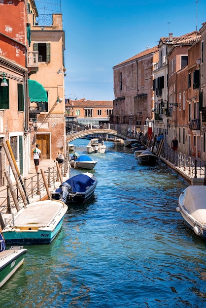 Barche sul canale stretto con ponte tra vecchi edifici residenziali