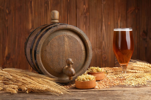 Barile di birra con luppolo e orzo su sfondo di legno