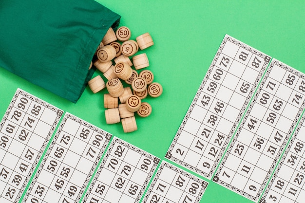 Barili di legno del lotto con borsa di stoffa e carte da gioco su sfondo verde.