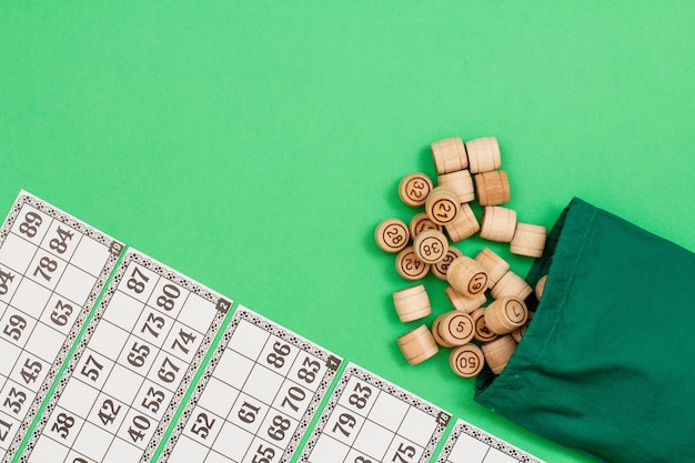 Barili di legno del lotto con borsa di stoffa verde e carte da gioco su sfondo verde. Lotto gioco da tavolo. Vista dall'alto con copia spazio a sinistra