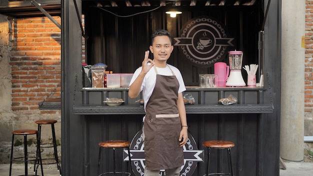 Barista asiatico che gesticola bene in un bar a tema container