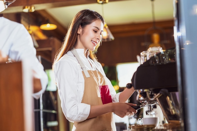 Barista asiatico che prepara tazza di caffè, caffè espresso con latte o cappuccino