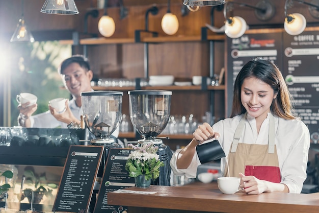 Barista asiatico che prepara una tazza di caffè espresso con latte o cappuccino per l'ordine del cliente