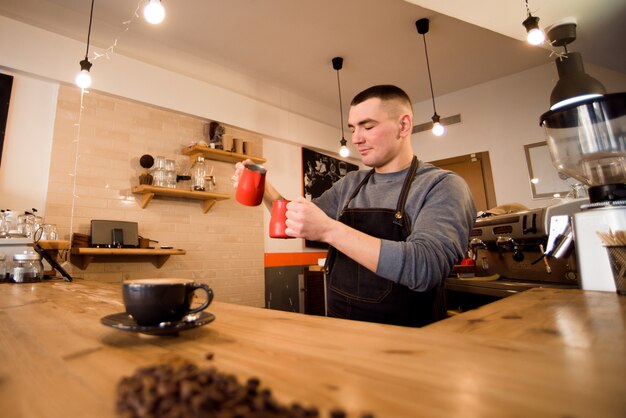 Barista bello che prepara tazza di caffè per il cliente in caffetteria.