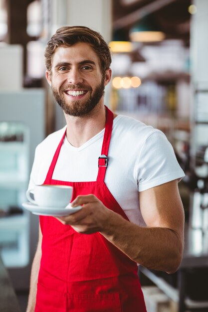 Barista bello che tiene una tazza di caffè