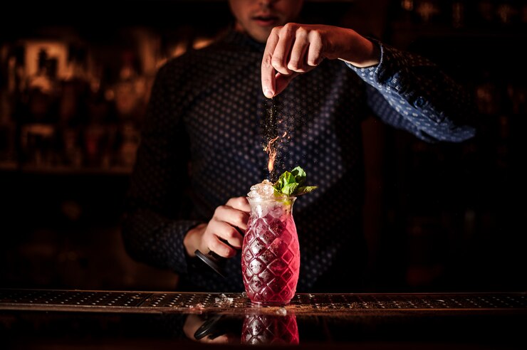 Barista che aggiunge le spezie al cocktail estivo fresco e dolce di mojito alla fragola